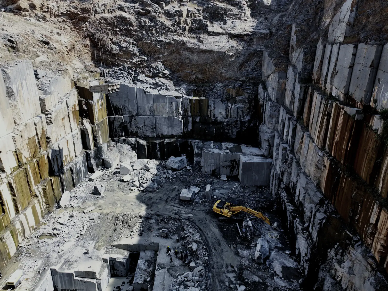 Excavator and crew working the floor of a granite quarry